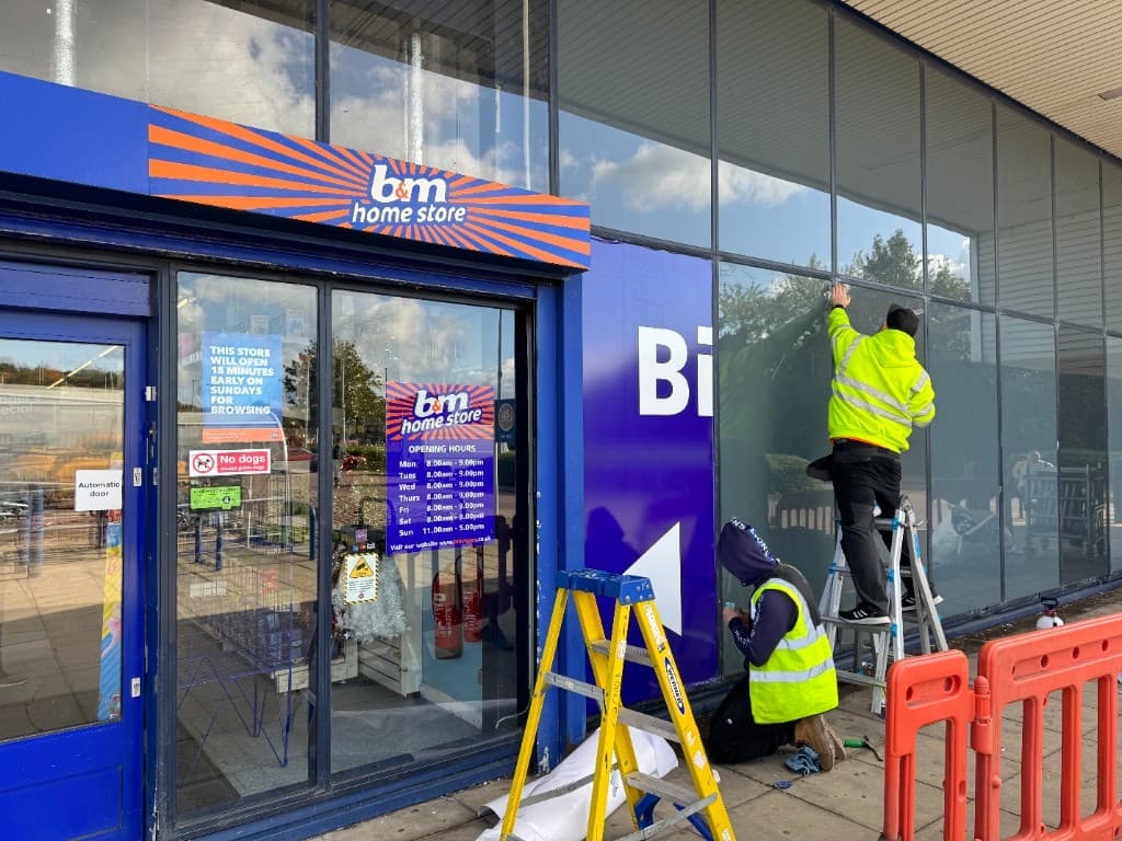 Installation team applying large format vinyl graphics to retail park glazing.