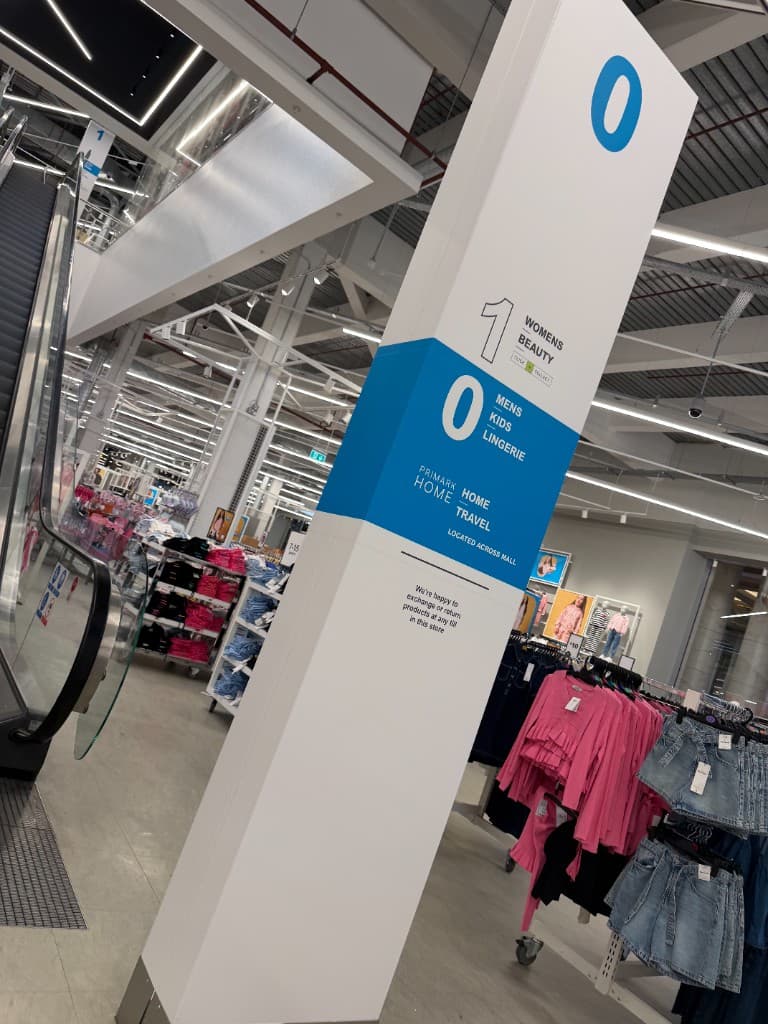 Primark Manchester store totem pole directional wrap — retail wayfinding