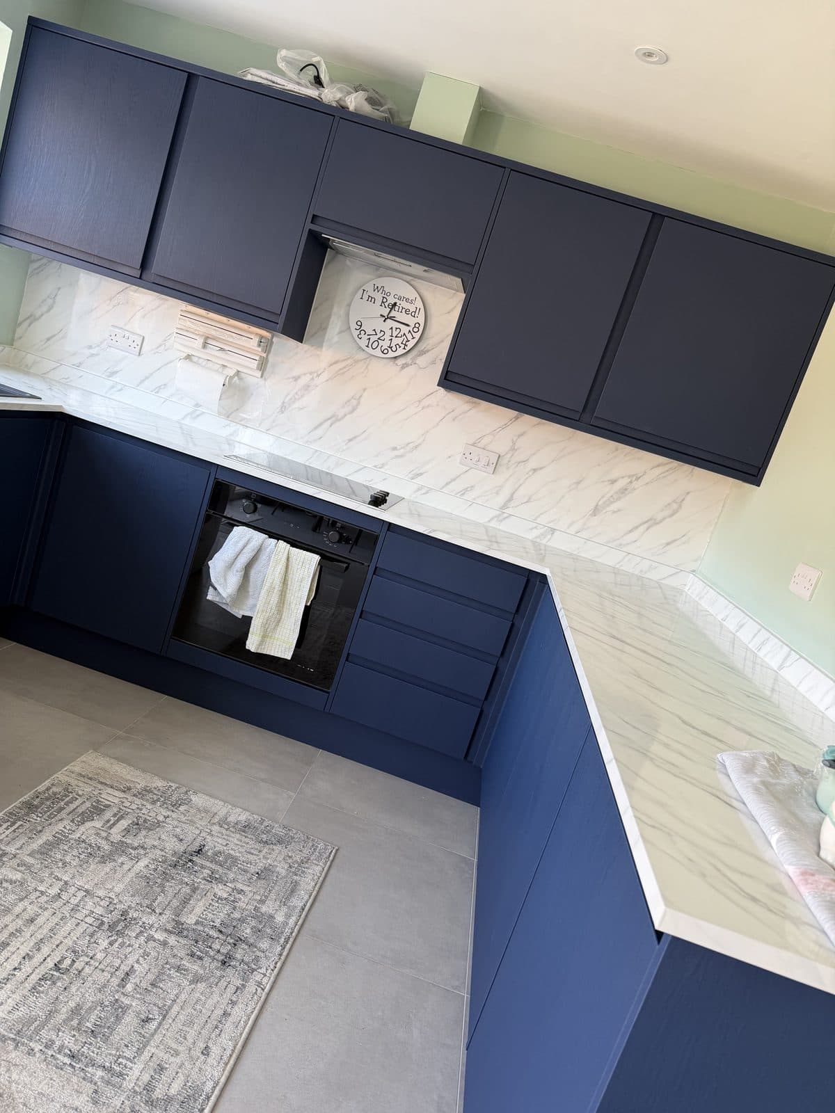Navy wood-effect kitchen wrap Doncaster — L-shaped kitchen with marble splashback after