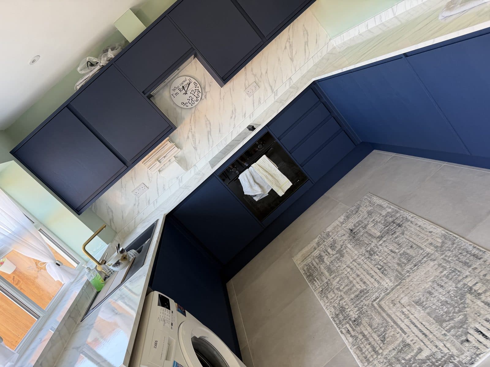 Navy kitchen wrap Doncaster — sink run with brass tap and white marble worktop after