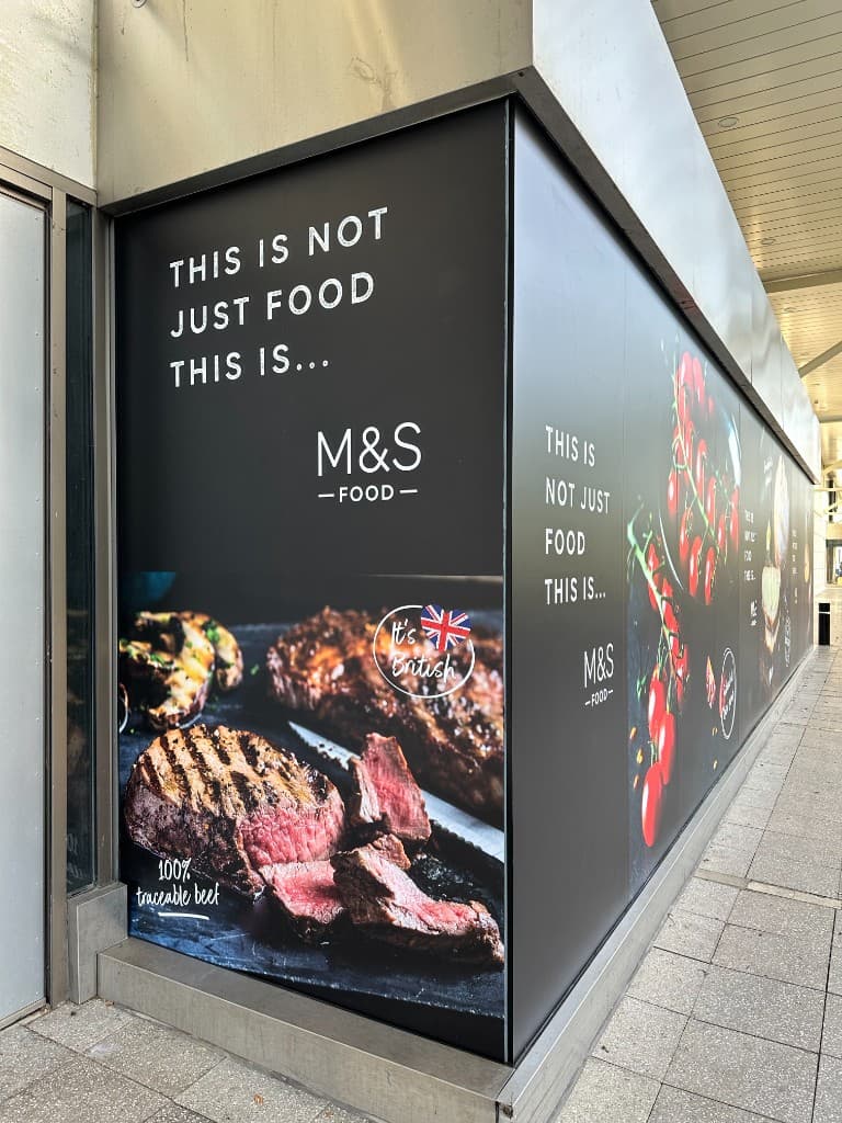 Corner view of a large food retail window graphic installed around a store entrance.