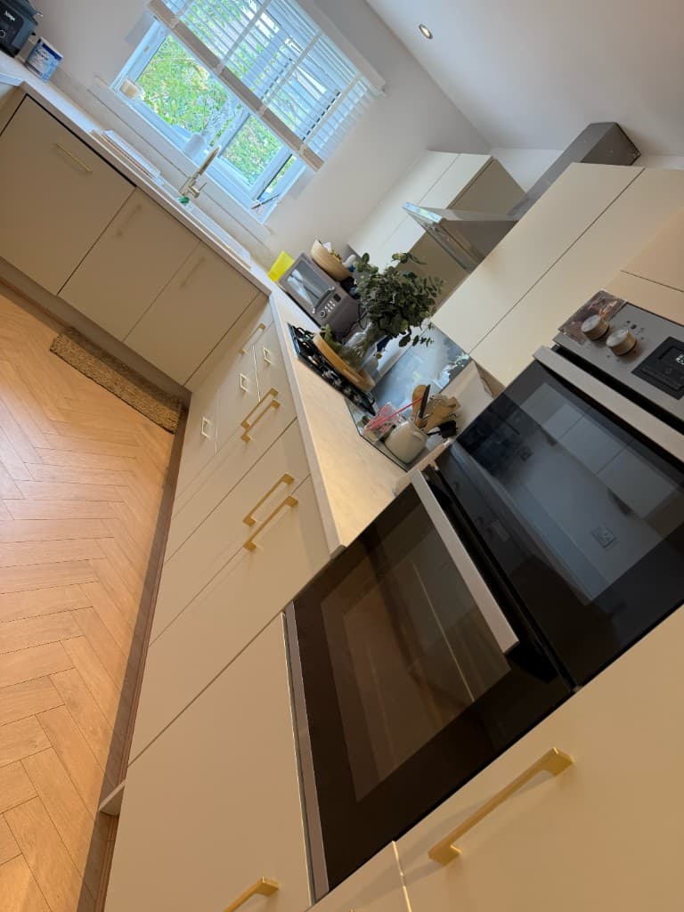 Matt ivory kitchen wrap with brushed brass handles installed by WRPX